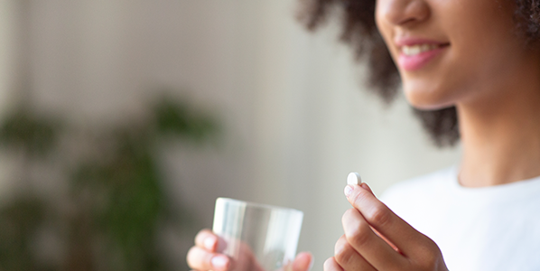 Woman taking a supplement with a glass of water